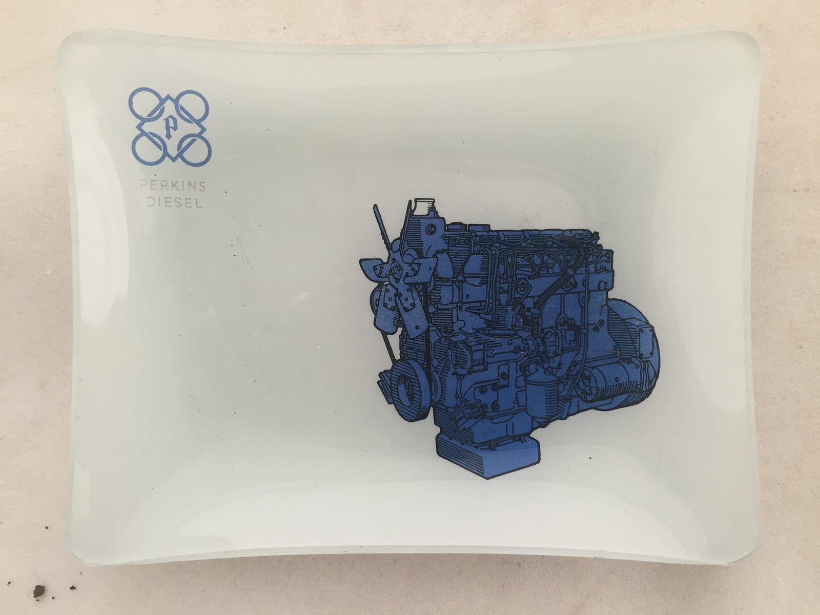 A Perkins Diesel opaque glass trinket dish with pictorial design depicting an engine.