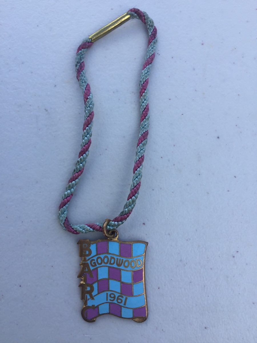 A BARC Goodwood mauve and pale blue chequer enamel badge for 1961, with appropriate coloured string,