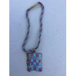 A BARC Goodwood mauve and pale blue chequer enamel badge for 1961, with appropriate coloured string,