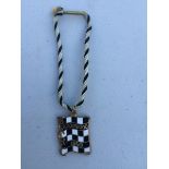 A BARC Goodwood black and white chequer enamel badge for 1959, with black and white string,