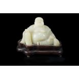 A pale celadon carving of a smiling Budai, modelled seated, the robe revealing the abundant belly,