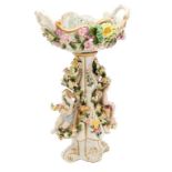 Alzata in ceramica decorata con fiori in alto rilievo e putti a tuttotondo dipinta a mano e