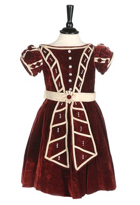 An unusual commemorative child's dress, 1863, of burgundy velvet with ivory satin piping,