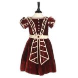An unusual commemorative child's dress, 1863, of burgundy velvet with ivory satin piping,