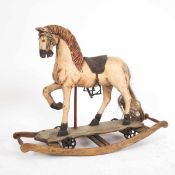 Schaukelpferd Holz, geschnitzt polychrom bemalt. Pferd mit Sattel auf zwei Kufen. H.: 68 cm, Br.: 85