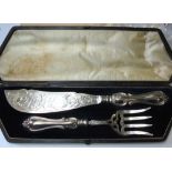 In thier original box, a pair of Victorian silver fish servers, engraved with scrolls and with the