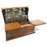 Oak three decanter tantalus with brass mounts, drawer below containing two small wine glasses and