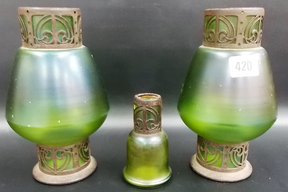 Pair of Loetz style green iridescent glass vases, the base and rim encased with metal scroll mounts,