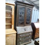 Early 20th century oak carved bureau bookcase with pair of lead glazed doors over the carved base,