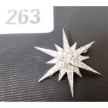 White metal diamond star brooch, the central diamond of 0.20ct approx, each long arm with three
