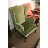 FURNITURE/ HOME - An original Parker Knoll wing back fireside armchair, covered in green fabric & in