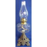 Single burner oil lamp with glass reservoir and cast metal base.