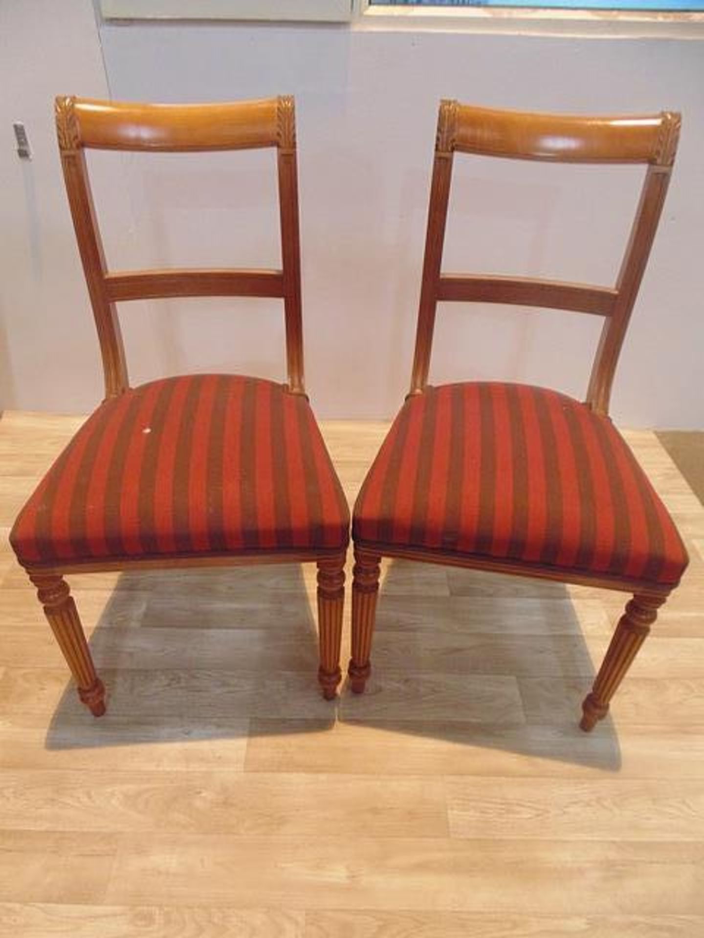 A set of four Regency style striped mahogany dining chairs, moulded top rails over a central