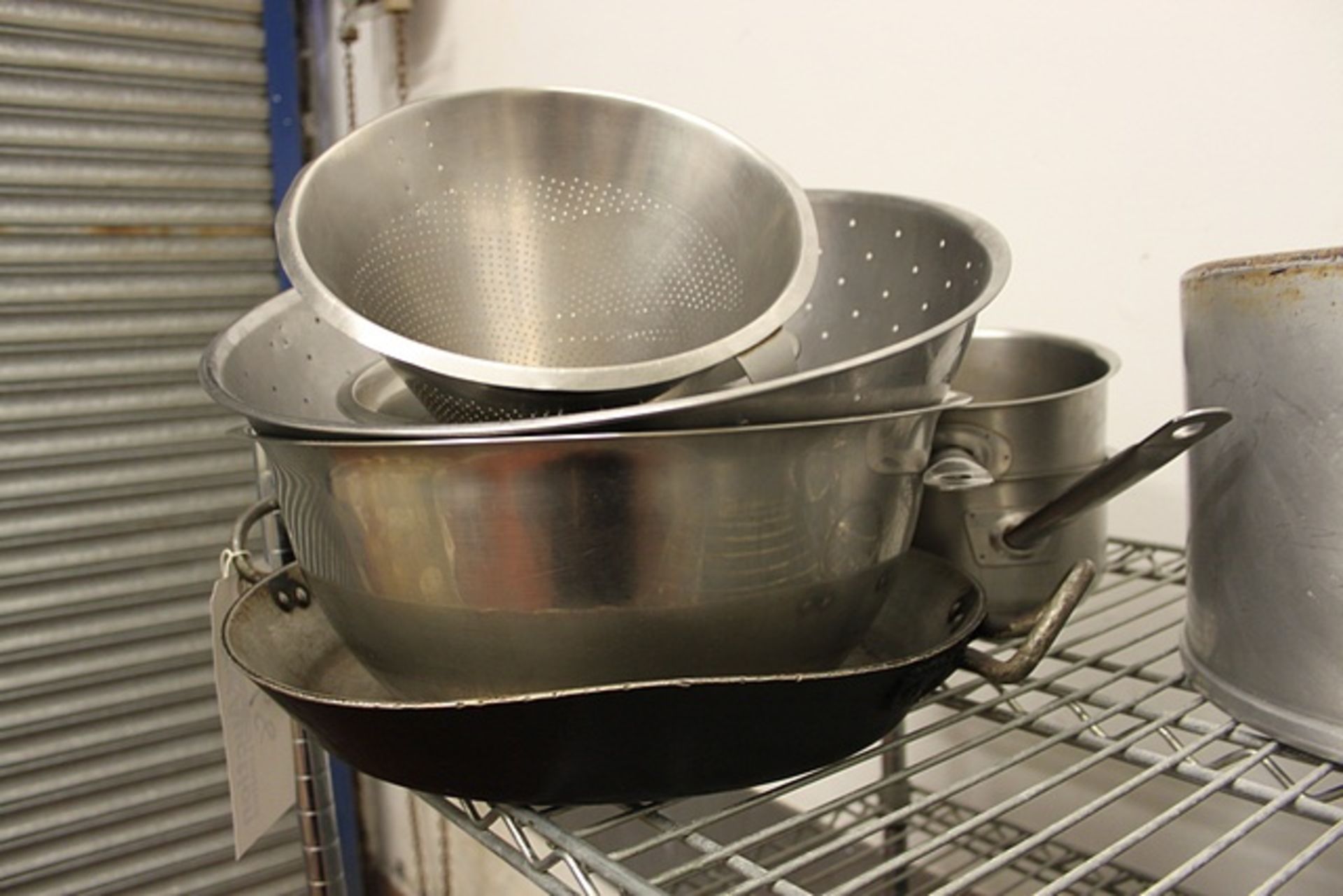 Various mixing bowls, collanders and stainless saucepans as found