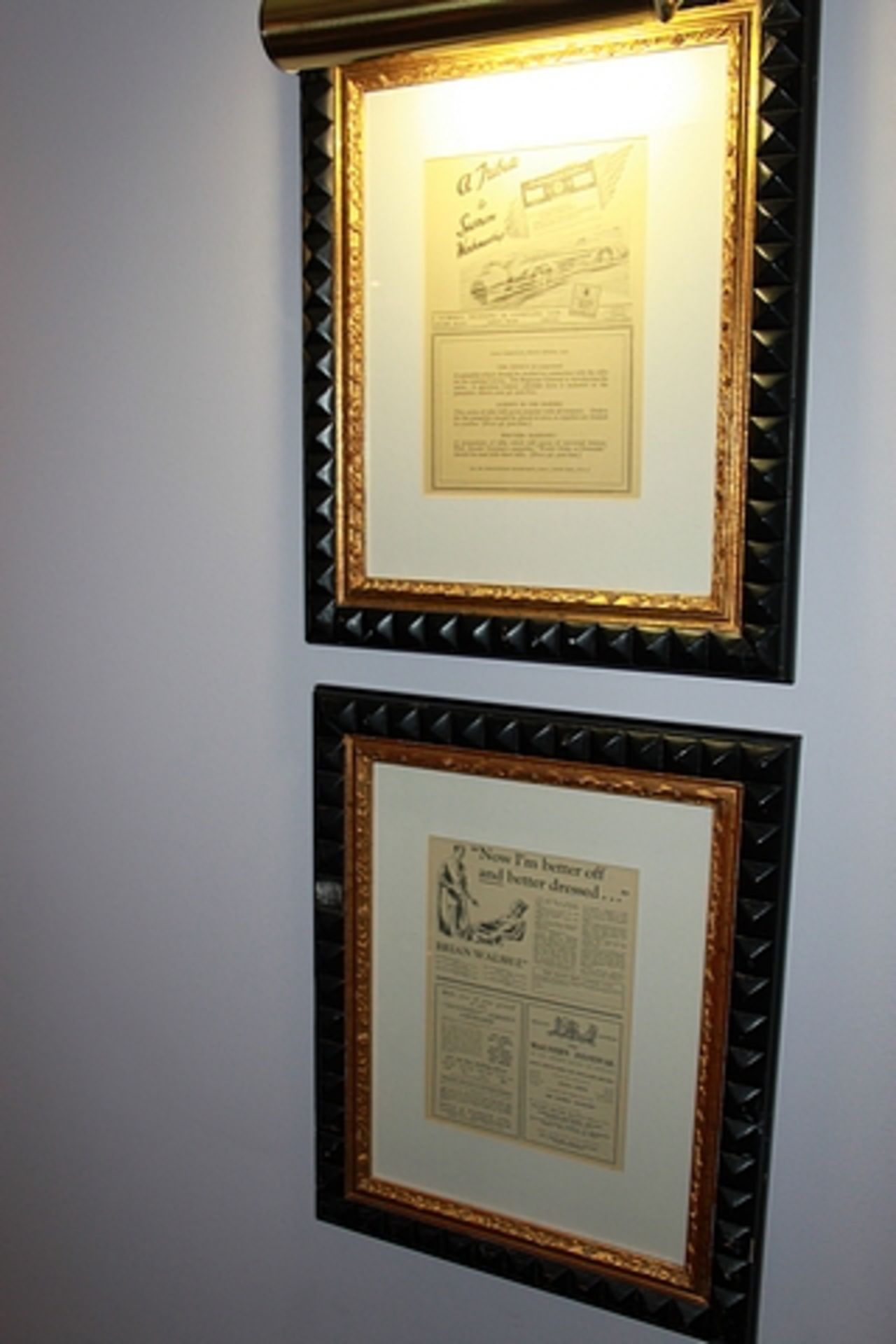 A pair of newspaper clipped posters , framed 440mm x 540mm with brass picture lamp