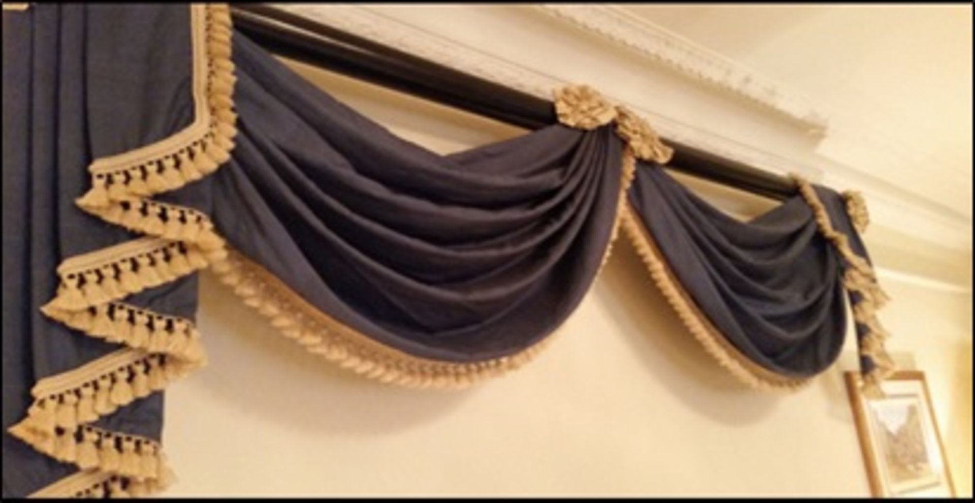 A blue gold swag pelmet valance on mahogany pole A pair of soft gold lined luxury drape curtains
