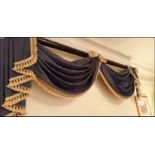 A blue gold swag pelmet valance on mahogany pole A pair of soft gold lined luxury drape curtains