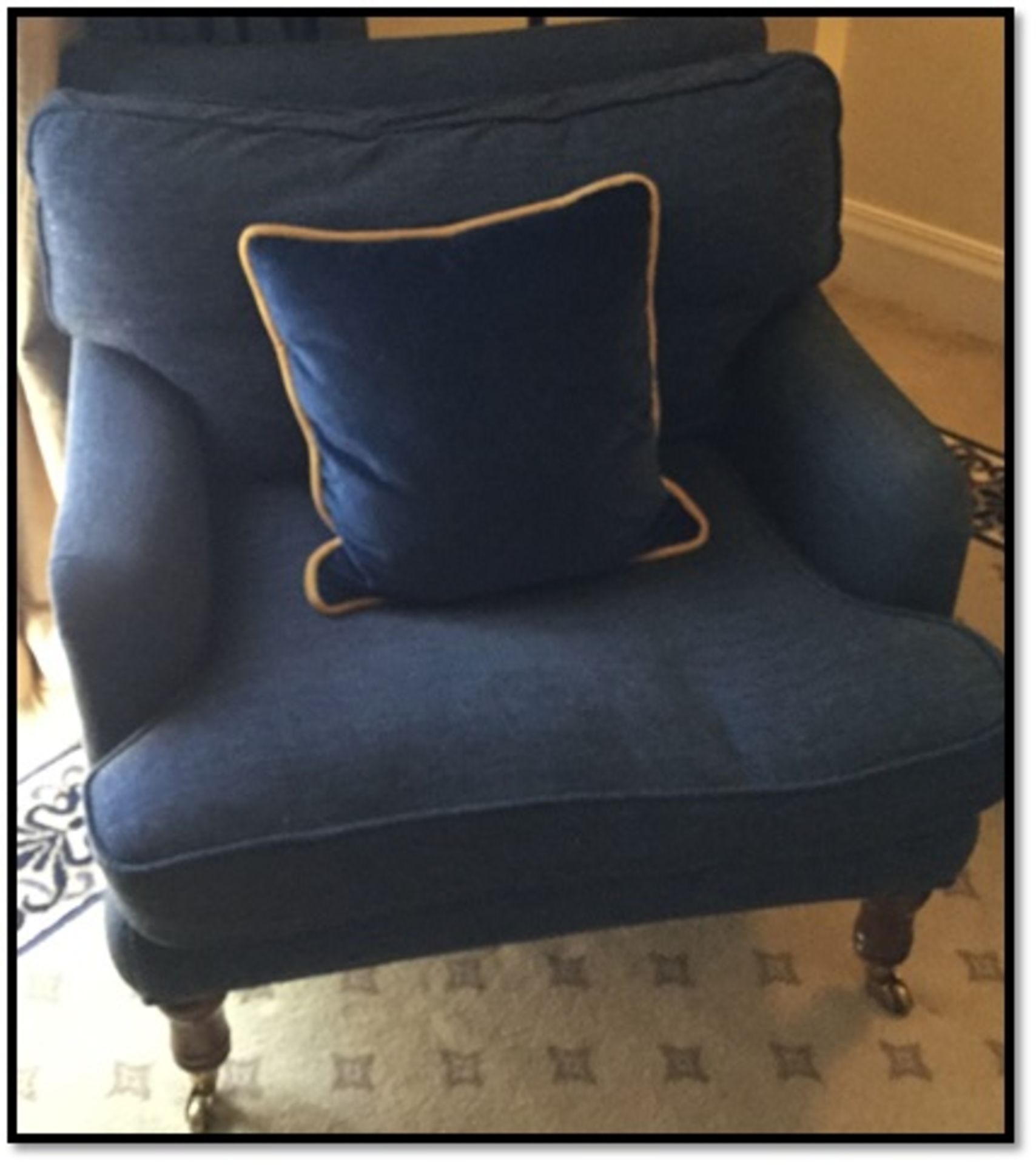 An upholstered blue armchair with pillow backrest cushion seat pad mounted on front castors