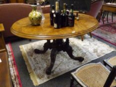 A mid-Victorian quartered veneered walnut loo table, the oval top on a four cluster column base with