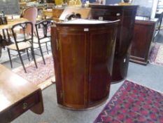 An early 19th century bowfronted inlaid mahogany hanging corner cupboard, with moulded cornice above