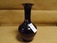 A Chinese monochrome black glazed porcelain vase, of baluster form, with trumpet neck, bearing