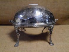 A late Victorian silver-plated breakfast warmer, engraved with foliate wreaths, raised on scroll pad