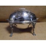 A late Victorian silver-plated breakfast warmer, engraved with foliate wreaths, raised on scroll pad