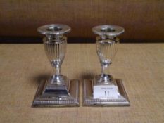 A pair of late Victorian silver dwarf candlesticks, London 1897, each of fluted urn form, with