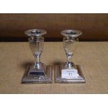 A pair of late Victorian silver dwarf candlesticks, London 1897, each of fluted urn form, with