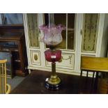 A Victorian cranberry glass and brass oil lamp, with ebonised base, columnar standard, cranberry