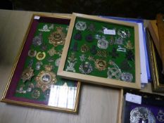 A collection of British military cap, shoulder and cross-belt badges, mounted in two frames,