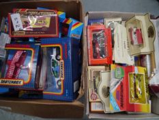 Two boxes containing boxed model vehicles including Matchbox and Lledo and Hamleys