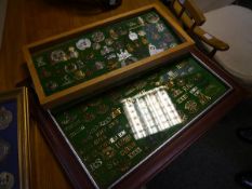 A collection of British military cap, shoulder and cross-belt badges, mounted in two frames,