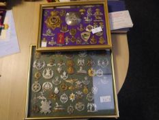 A collection of British military cap, shoulder and cross-belt badges, mounted in two frames,