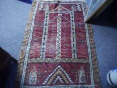 Caucasian prayer rug, the centre panel with stylised arch enclosed within a scroll border, red field