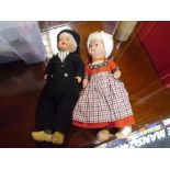 A pair of vintage Dutch boy and girl dolls, she with glass eyes, he painted, both in wooden clogs