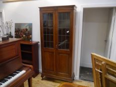 An oak bookcase cabinet in the Arts and Crafts taste, c. 1900, with a pair of lead-glazed panelled