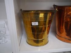 A brass log or coal bucket, c. 1900, decorated with incised bands and with swing handle.