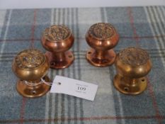 A set of four door knobs with copper finish, each cast with a thistle