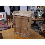 A small pine hanging cabinet, with galleried top, panelled door and fitted interior. 45cm by 33cm by