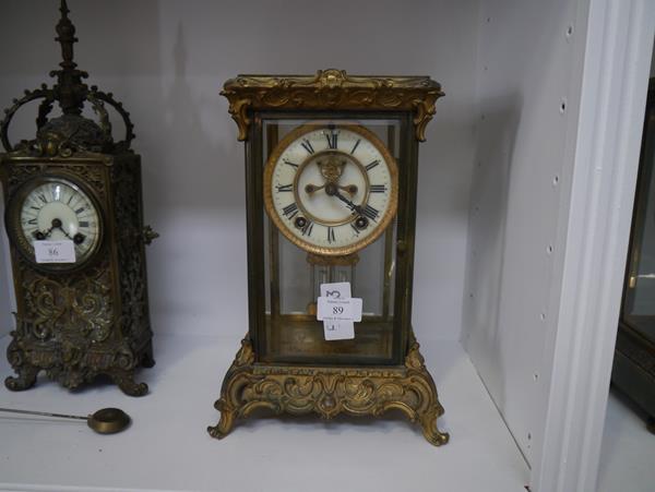 A gilt-metal four-glass mantel clock, c. 1910, the base and rest cast with rococo scrolls, the cream