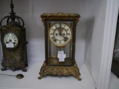 A gilt-metal four-glass mantel clock, c. 1910, the base and rest cast with rococo scrolls, the cream