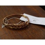 A 9ct gold bangle, chased and cast with entwined scrollwork, fitted with safety chain. 11 grams