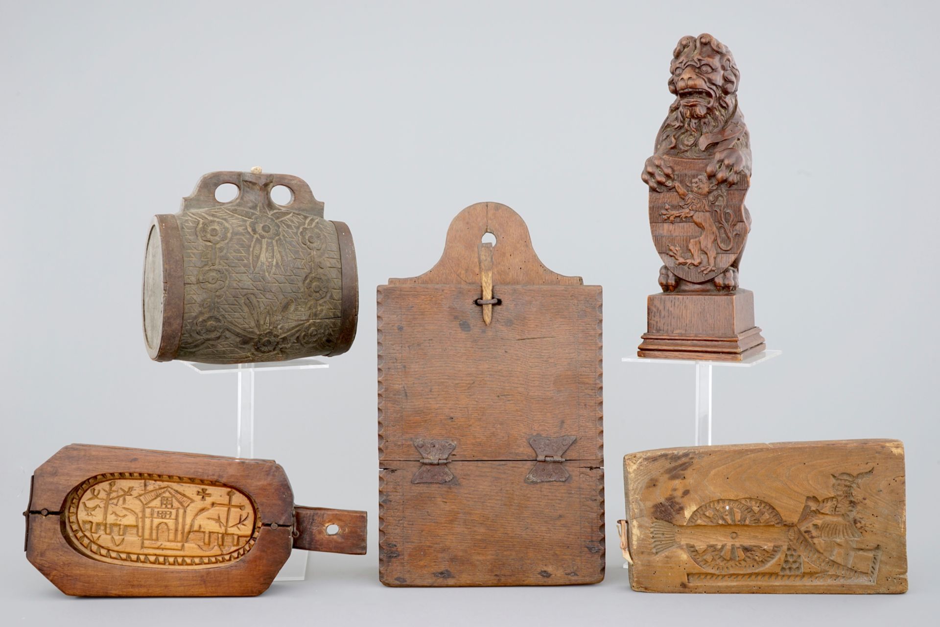 Various wood objects: a lion of Bruges, a butter mold, a cookie mold, a school bag and a wine jug,