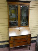 An Edwardian mahogany and line inlaid fall front bureau bookcase with a shaped cornice over twin