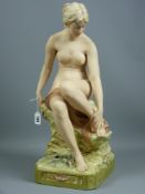 A good Royal Dux figure of a nude female seated upon a rocky base, semi-gloss and gilt highlighting,