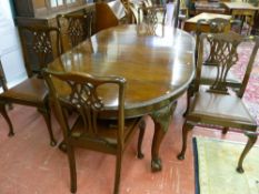 A good early 20th Century carved edge oval mahogany wind-out dining table with two extra leaves on
