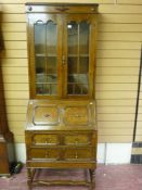 An early 20th Century Jacobean style oak bureau bookcase, the twin glazed bookcase doors with double