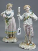 A pair of German porcelain figures in 18th Century style dress of a young standing man with a