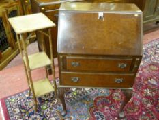 A walnut two drawer fall front bureau on carved cabriole supports and a bamboo three tier stand